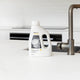 Bottle of ecostore Dishwasher Powder on a white kitchen counter.