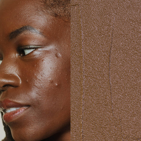 Model next to swatch of Elate Beauty Creme Concealer in the shade 'CN7', for deep neutral skin tones. A two-in-one concealer and illuminator formulated with evening primrose oil, designed to heal and conceal blemishes.