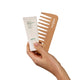 A hand holding a white tube of Endota Signature Blended Hair Mask next to a light natural wood hair comb with the Endota brand name printed on it, set against a solid white background.