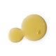 A small dollop of endota Phyto Renewal Oil on a white surface. The oil has a smooth, slightly amber hue and a glossy texture, reflecting light to highlight its rich consistency. The white background emphasises the clarity and quality of the oil.