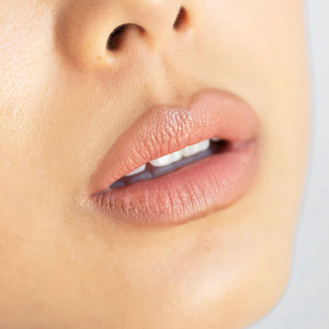 Ere Perez Acai Lip Pencil Pout lifestyle close up of a woman's lips in a soft peach nude shade, face cropped, styled lifestyle photo