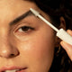 Ere Perez Aloe Gel Lash & Brow Mascara Clear 10ml lifestyle close up of a woman brushing her eyebrow with the spoolie wand, styled lifestyle photo