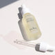 Ere Perez Australian Blue Cypress Face Nectar 30ml lifestyle shot of the dropper bottle and its dropper lying on a pale surface