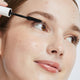 Ere Perez Avocado Waterproof Mascara Black lifestyle close up of a woman's face as the mascara wand brushes her upper lashes, soft light