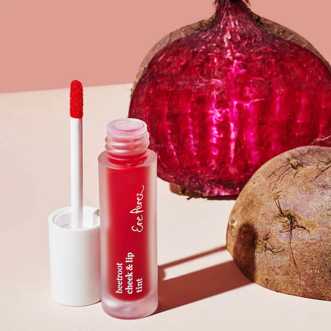 Red lip tint with applicator and beetroot in the background on a neutral surface