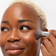 Ere Perez Eco Vegan Brush Multipurpose lifestyle shot of a smiling woman with short blonde hair and deep skin using the brush on her cheek