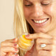 Ere Perez Papaya SOS Marmalade 30g lifestyle shot of a smiling woman with blonde hair holding the open jar of balm, close up shot