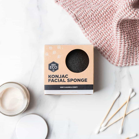 Charcoal konjac sponge in packaging on a marble surface with a pink cloth.