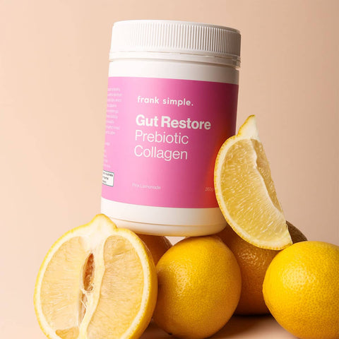 Supplement container labeled 'Gut Restore Prebiotic Collagen' 260g by Frank Simple with lemons on a beige background.