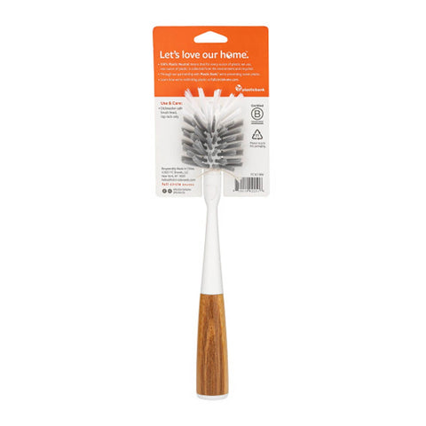 A reusable dishwashing brush with a white handle and a brown wood-grain lower section, packaged on a white and orange cardboard backing. The brand name 'Sustainable' is visible on the packaging.