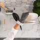 Person wearing black gloves washing dishes in a kitchen with marble countertop and geometric tile backsplash.