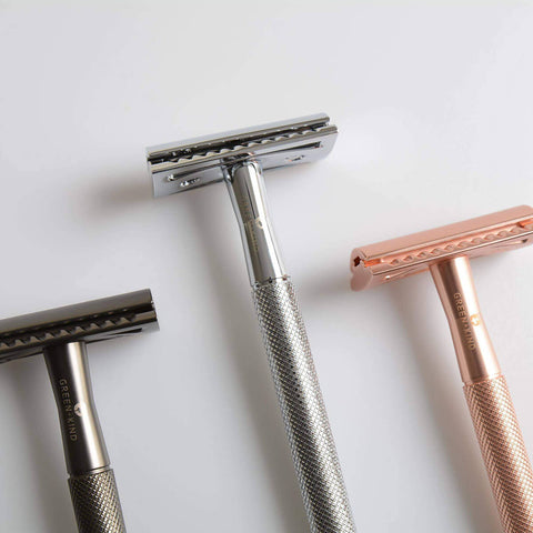 Three razors, two silver and one rose gold, on a light gray background.