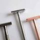 Three razors, two silver and one rose gold, on a light gray background.
