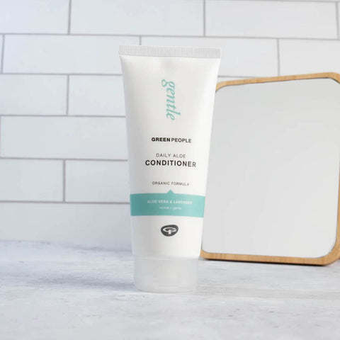 Green People daily aloe conditioner bottle on a bathroom counter with a mirror in the background