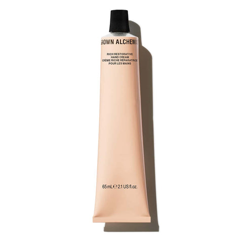 Hand cream tube of Grown Alchemist Rich Restorative Hand Cream 65ml with black cap with a shadow on a white background.