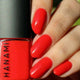 Hand with red nail polish holding a red nail polish bottle labeled 'HANAMI'.