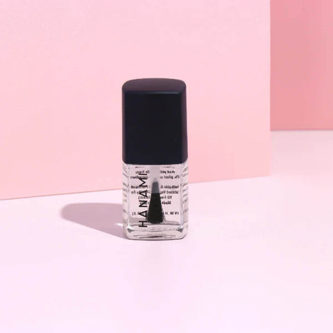 Bottle of nail polish with black cap on a pink background