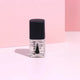 Bottle of nail polish with black cap on a pink background