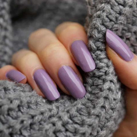 Hand with purple nail polish on a gray textured background