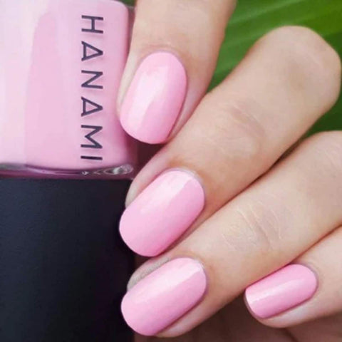 Pink nail polish on nails with a bottle of Hanami nail polish in the background.