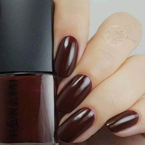 Nail polish bottle with a hand showing dark brown nails