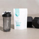 Happy Way creatine powder on bench next to branded smoothie cup and weights