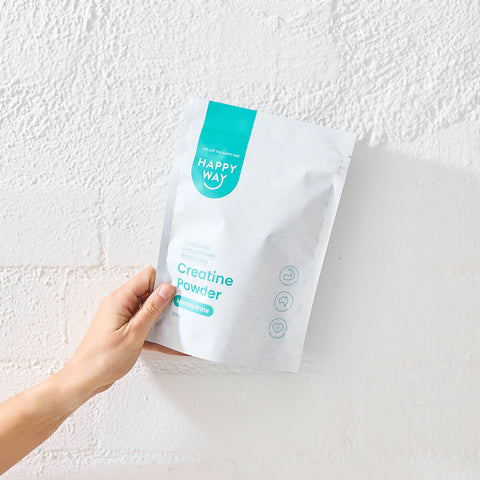 Happy Way creatine powder pictured against painted white brick wall 