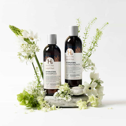 Two bottles of shampoo and conditioner with flowers on a white background.