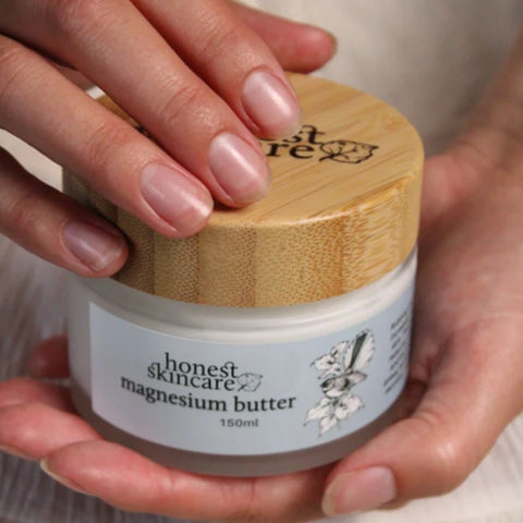Honest Skincare Magnesium Butter 150ml lifestyle close up of two hands holding the jar with its bamboo lid, styled lifestyle photo
