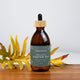Honest Skincare Organic Castor Oil 250ml lifestyle shot of the dropper bottle on wood beside yellow flowers, styled lifestyle photo
