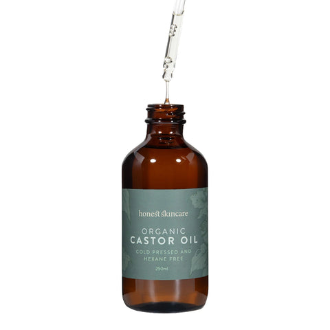 Honest Skincare Organic Castor Oil 250ml open amber bottle with its dropper lifted and a drop falling on a plain white background