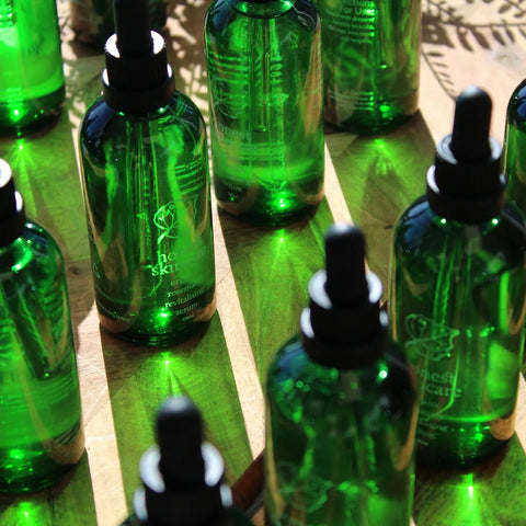 Honest Skincare Organic Rosemary Revitalising Hair Serum 100ml lifestyle close up of rows of green glass dropper bottles, styled lifestyle photo