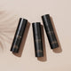 Three bottles of INIKA Organic Liquid Foundation on a beige background.