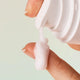 INIKA Organic Pure Biome Gentle Milk Cleanser 100ml lifestyle close up of a fingertip taking a dab of white cleanser from the pump
