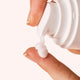 INIKA Organic Pure Biome Hydro-Fluid Moisturiser 50ml lifestyle close up of a fingertip taking a dab of white cream from the pump bottle