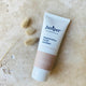 Tube of Juniper Regenerative Facial Exfoliant on a beige background with a dried plant. 