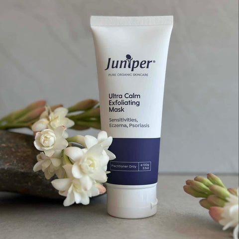 Tube of Juniper Ultra Calm Exfoliating Mask with flowers in the background.