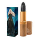 Lipstick tint next to box packaging that pictures a woman in a gothic outfit. Gold lipstick case with flower detail on lid.