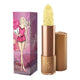 Moisture stick in a gold lipstick case, next to pink box packaging, picturing a woman in pink holding a cupcake.
