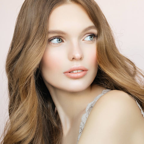Young woman with plump, hydrated soft peach toned lips wearing moisture stick lip balm. 