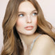 Young woman with plump, hydrated soft peach toned lips wearing moisture stick lip balm. 