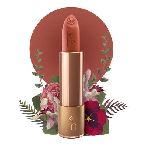 Peachy warm nude shade, gold lipstick case against a floral background. Lipstick detailed with KM initials & flower on the tip. Natural, clean cosmetics.