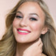 Young woman with blonde hair & light skin tone, blue eyes, smiling while wearing carnation mist lipstick.