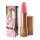 Lipstick next to box packaging that pictures a woman in a pink bathrobe sitting in front of a mirror vanity. Gold lipstick case with flower detail on lid. Natural, clean cosmetics.