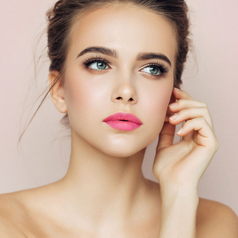 Young woman with fair skin & brunette hair wearing camellia morning lipstick.
