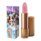 Lipstick next to box packaging that pictures a woman in a blue dress & beret drinking coffee. Gold lipstick case with flower detail on lid. 