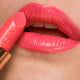 Close-up of poppy passion lipstick applied on the lips. 