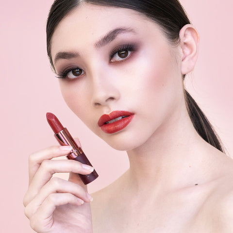 Young woman with fair skin tone & dark hair wearing fiery ruby lipstick, wearing complementary brown & bronze eye makeup. 