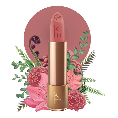 Lipstick detailed with KM initials & flower on the tip, set against a floral background. 