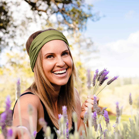 Woman with a green headband holding lavender flowers in a field.